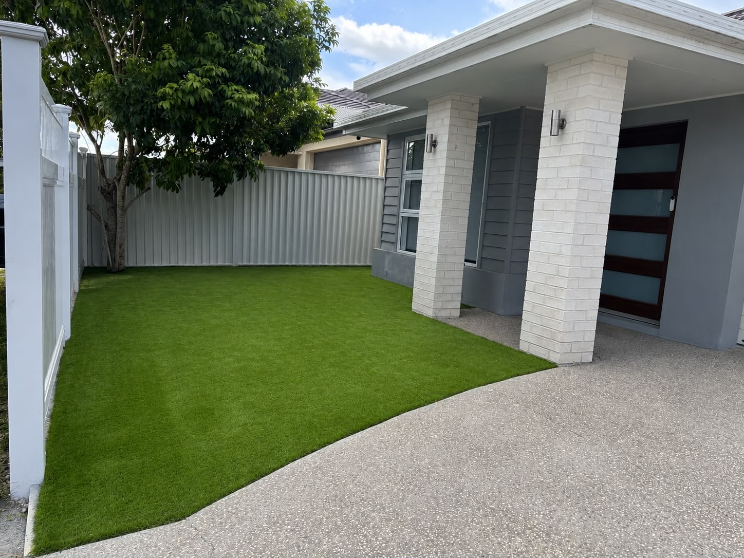 Synthetic grass front yard with Colorbond fence and exposed aggregate driveway