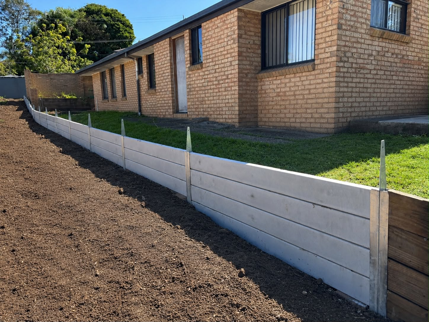 New concrete sleeper retaining wall beside a brick home
