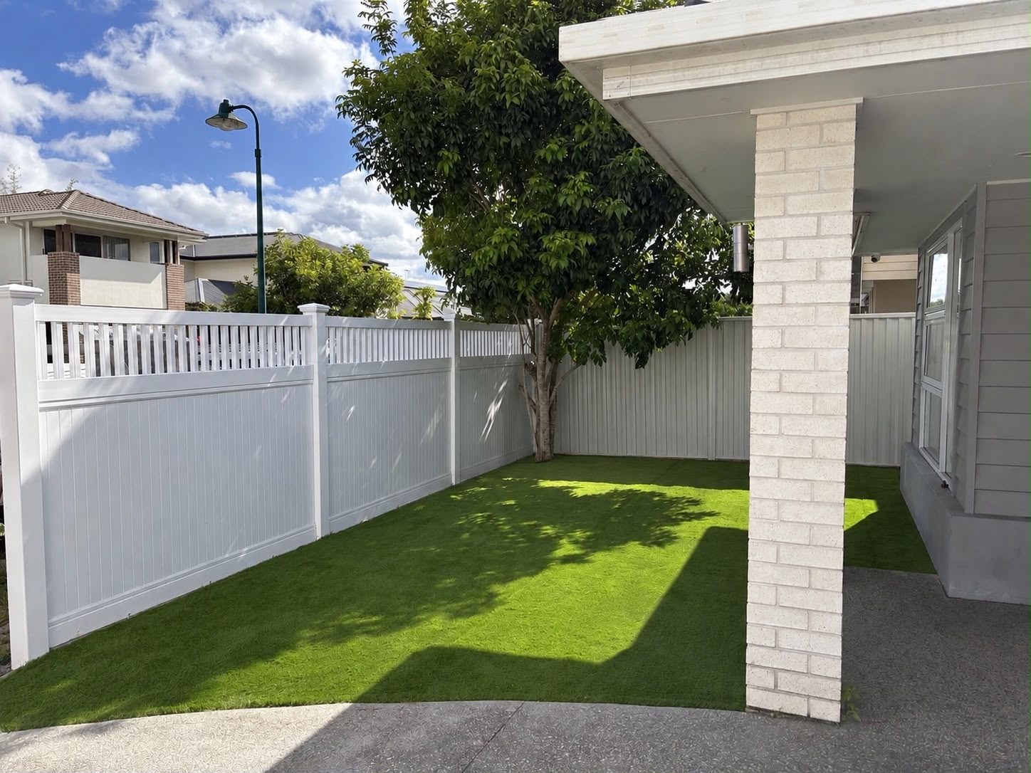 White PVC fencing and synthetic grass in a landscaped yard