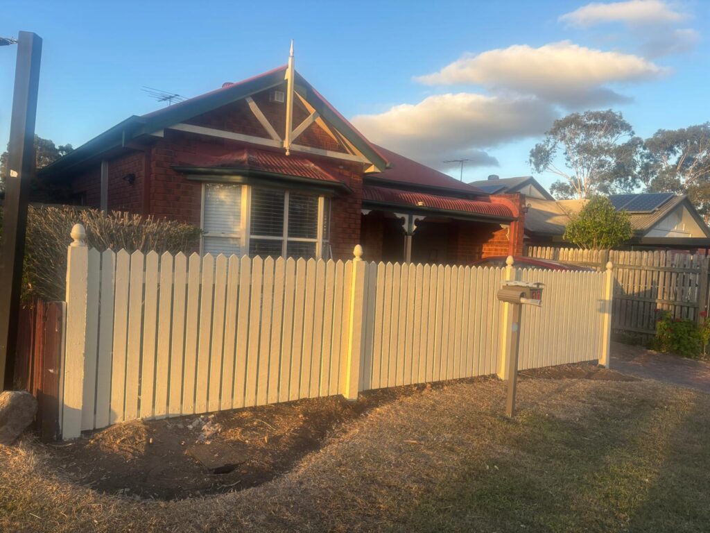 Painted hardwood picket fence and pedestrian gate beside the brick home in Forest Lake