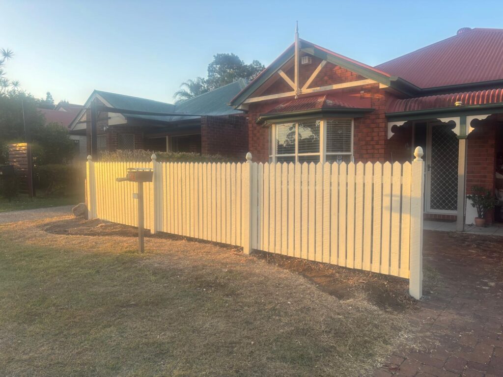 Angled view of the painted hardwood fence along the front lawn in Forest Lake