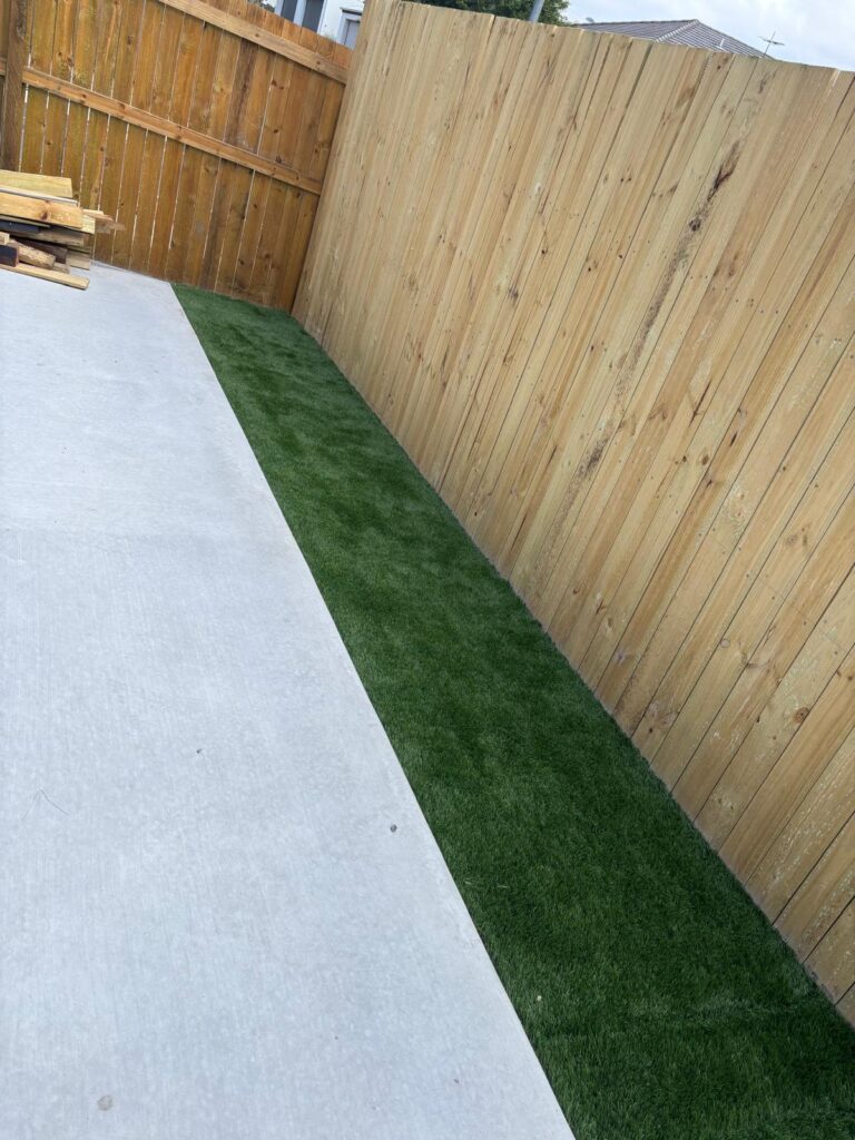 Synthetic grass strip between the timber fence and concrete path in Richlands
