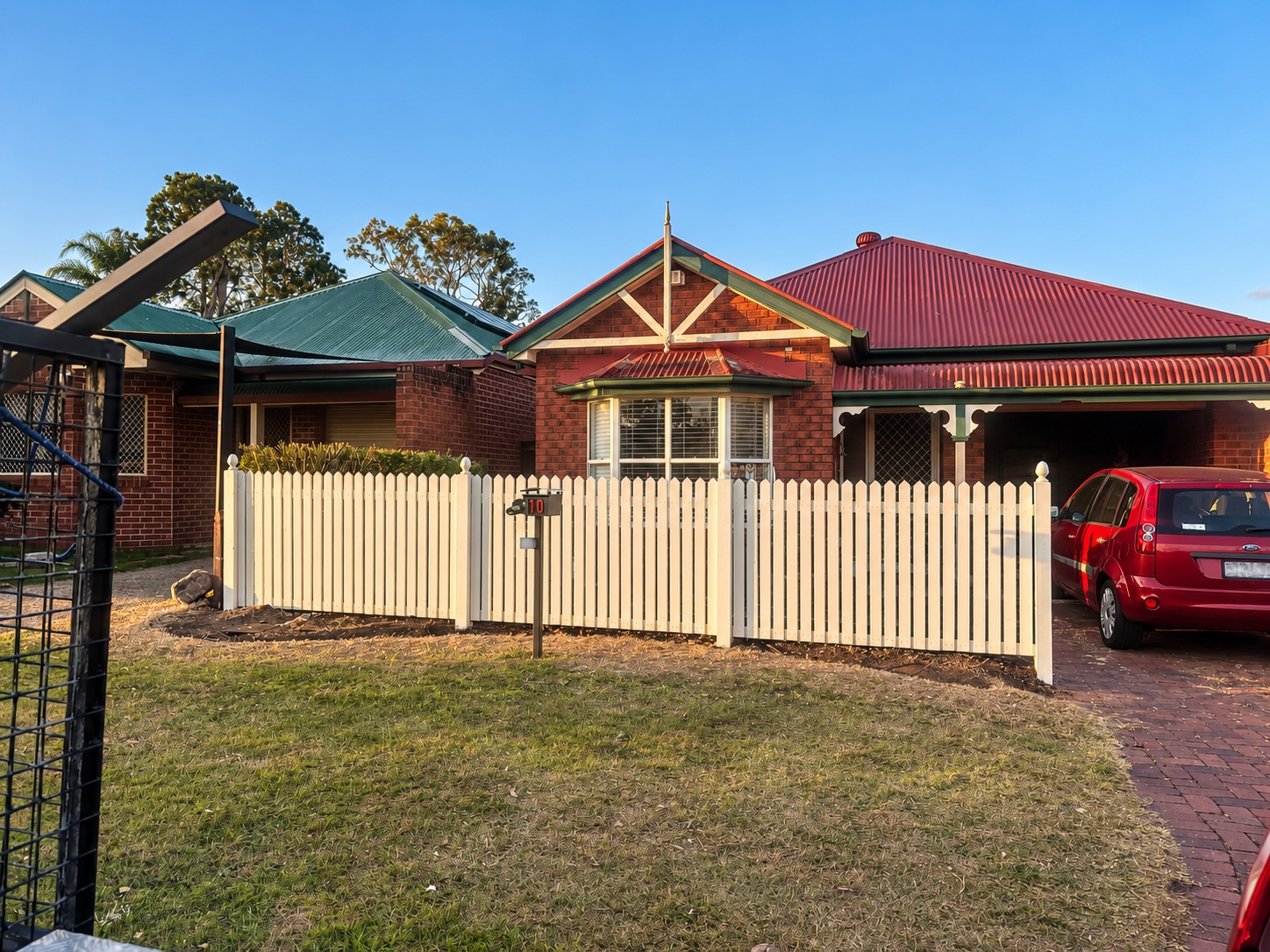 Painted hardwood picket fence and gate in front of the brick home in Forest Lake