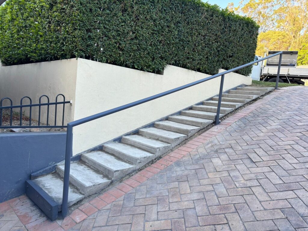 Concrete stairs with handrail and rendered wall